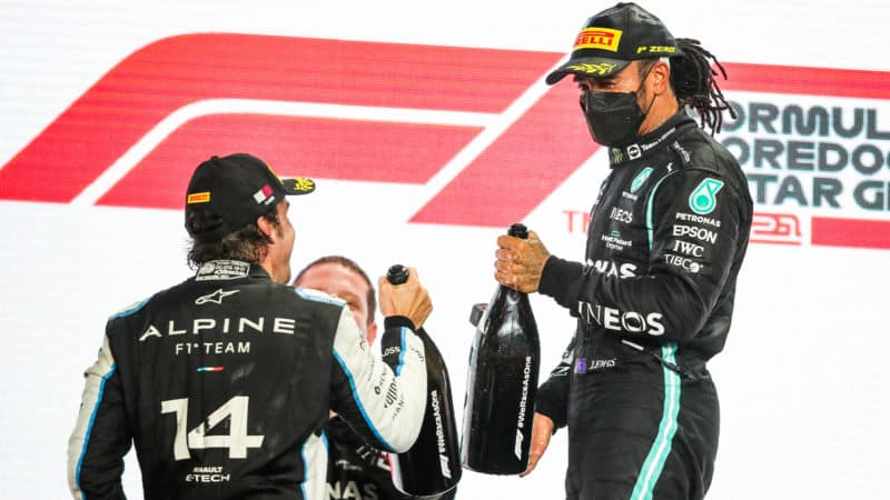Lewis Hamilton clinks champagne bottles with Fernando Alonso on the 2021 Qatar GP podium