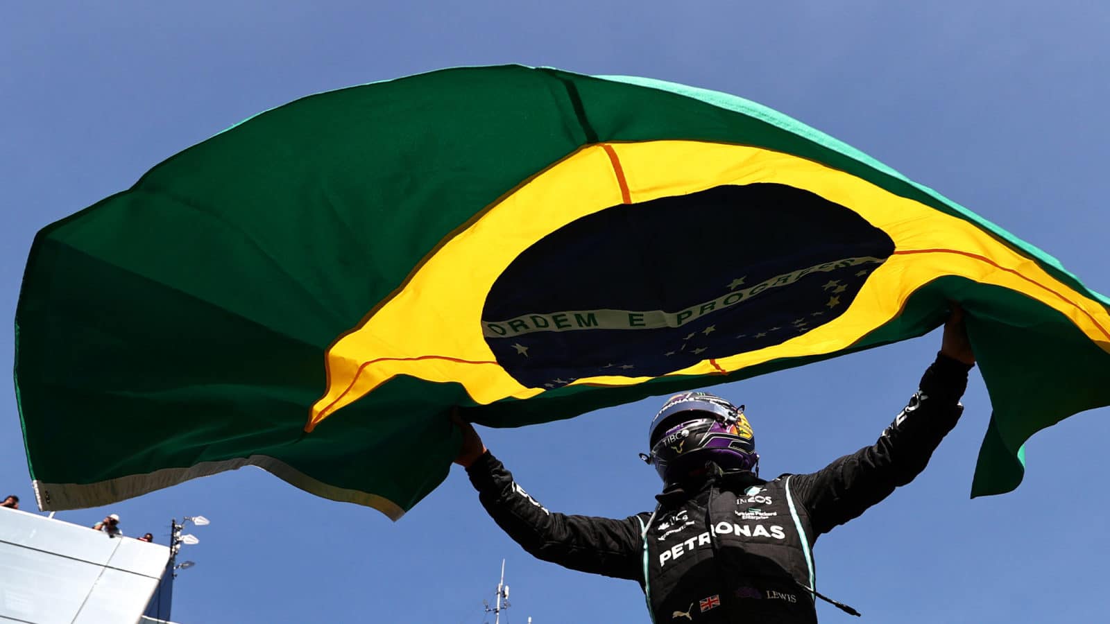 Lewis hamilton waves Brazilian flag after winning 2021 grand prix at Interlagos