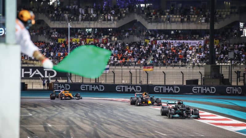 Green flag waves as Lewis Hamilton leads Max Verstappen on the last lap of the 2021 Abu Dhabi Grand Prix