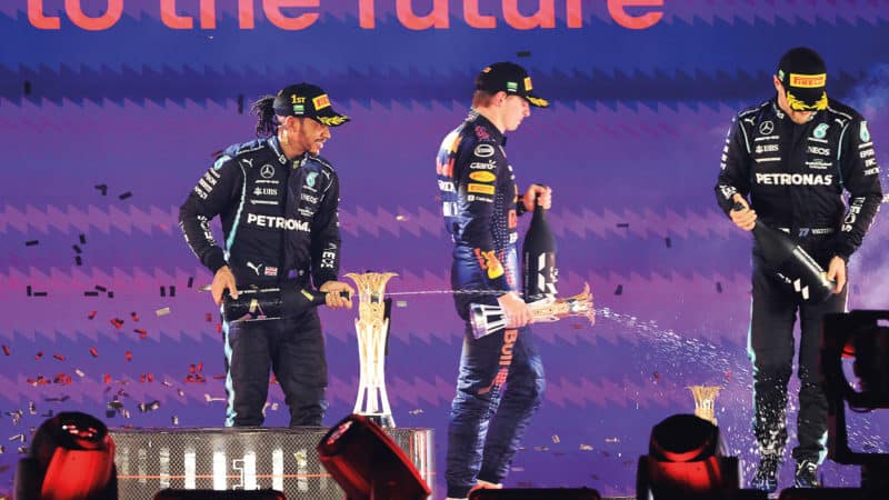 Max Verstappen walks off the podium as Lewis Hamilton sprays champagne after the 2021 Saudi Arabian Grand Prix