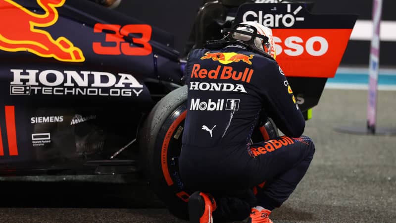 Max Verstappen crouches down at the wheel of his Red Bull after 2021 Abu Dhabi GP