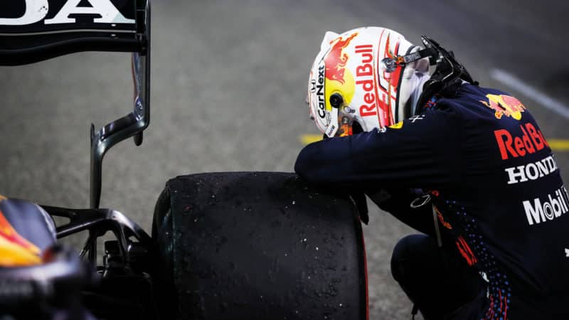 Max Verstappen crouches over the tyre of his Red Bull after winning the 2021 F1 championship