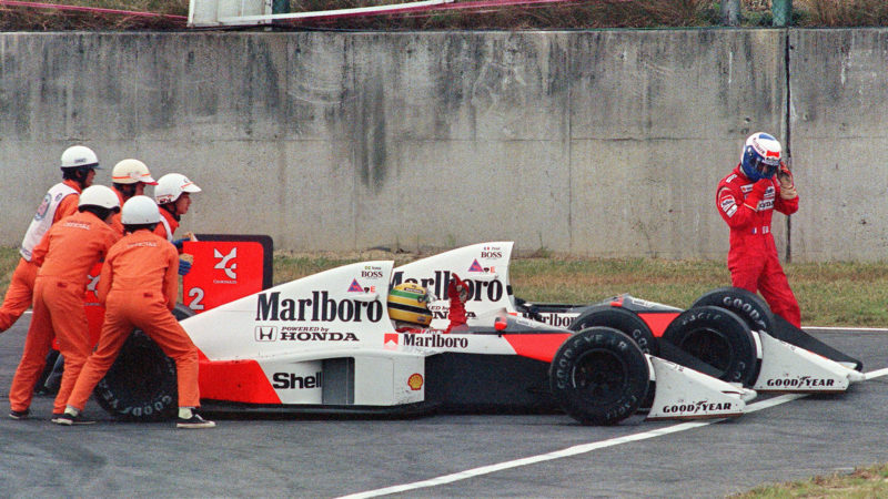 Ayrton Senna of Brazil is given a push from circuit marshals for a restart while his teammate and bitter rival Alain Prost of France leaves his car to abandon the race after the two collided in a chicane during the Japan Formula One Grand Prix in Suzuka 22 October 1989. Senna received the chequered flag but was later disqualified after being accused of receiving an illegal push from marshals and of taking a short cut through the chicane. AFP PHOTO TOSHIFUMI KITAMURA (Photo by Toshifumi KITAMURA / AFP) (Photo credit should read TOSHIFUMI KITAMURA/AFP via Getty Images)