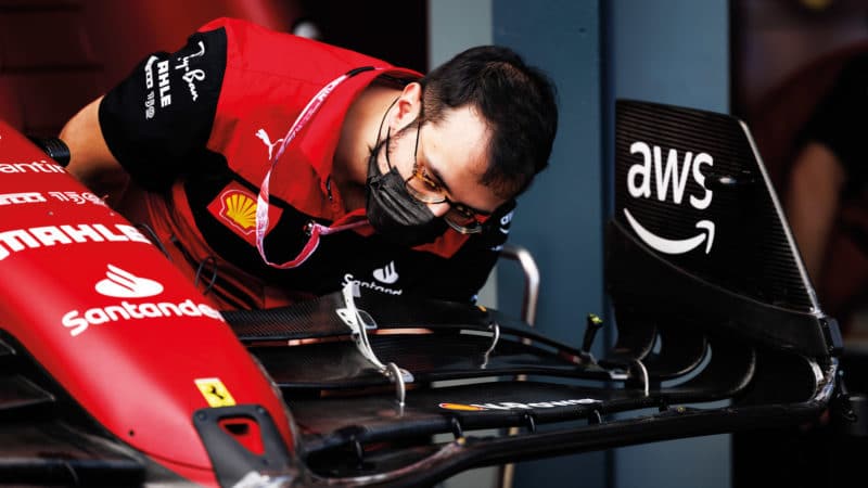 Ferrari engineer examines front wing of F1 car