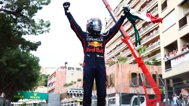 Sergio Perez raises his arms holding a MExican flag after winning the 2022 Monaco Grand Prix