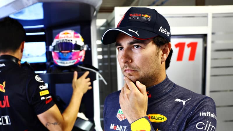 Sergio Perez with hand on chin in the Red Bull pits