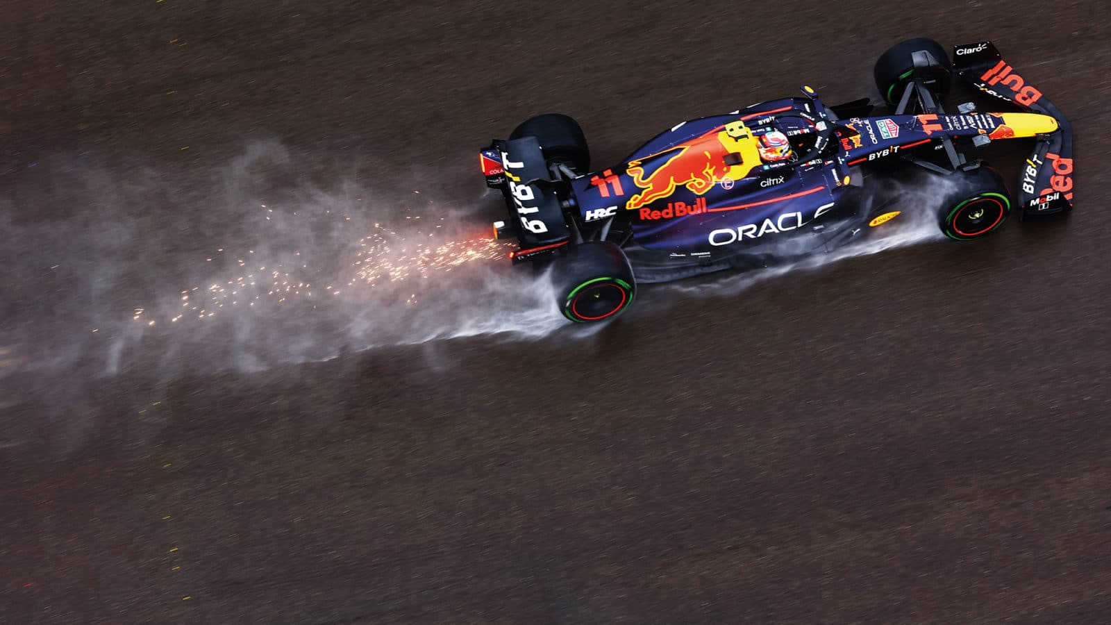 Sparks fly through the spray from the Red Bull of Sergio Perez