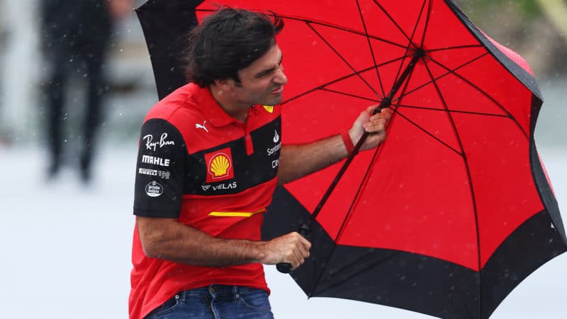 Carlos Sainz struggles with an umbrella in the rain ahead of the 2022 Canadian Grand Prix