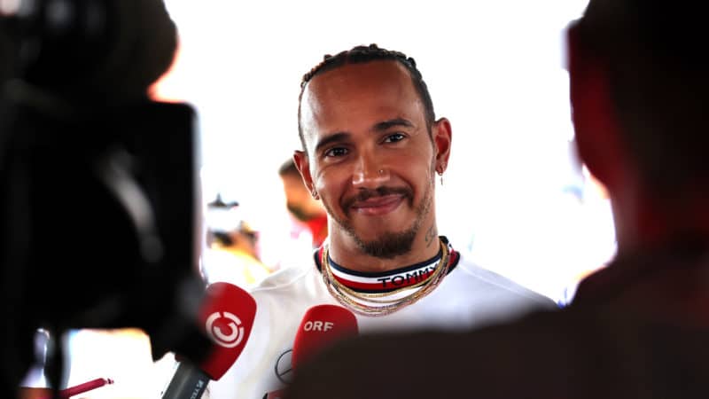 Lewis Hamilton smiles in front of cameras as he is interviewed