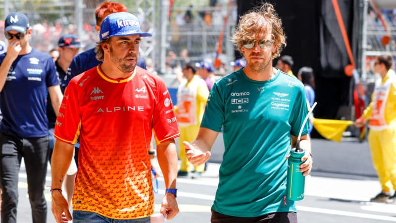 Fernando Alonso walks next to Sebastian Vettel