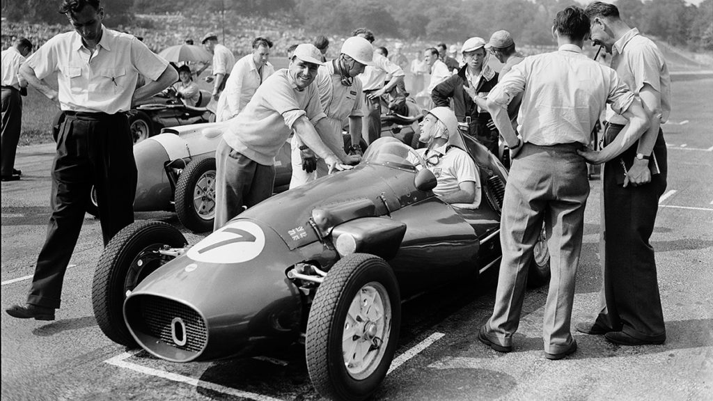 John Cooper smiles for the camera while Moss chats before the start of the 1953 Coronation Trophy