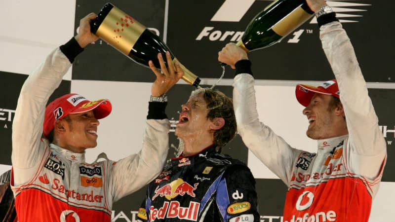 Red-Bull-driver-Sebastian-Vettel-celebrates-winning-the-2021-F1-championship-on-the-2010-Abu-Dhabia-podium-with-McLaren-drivers-Sebastian-Vettel-and-Jenson-Button