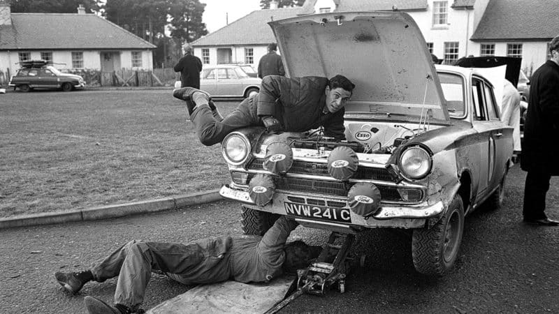 Jim Clark assists with maintenance on his Lotus Cortina during the 1966 RAC Rally