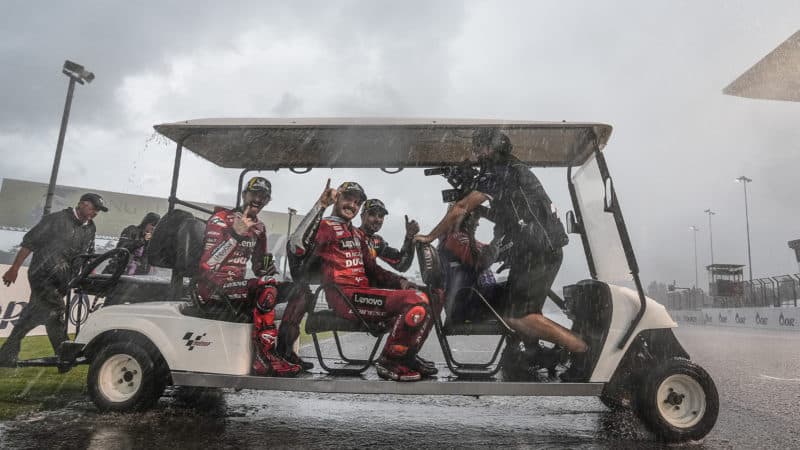 Miguel Oliveira Jack Miller and Pecco Bagnaia in a golf cart as rain pours down after the MotoGP Thai GP