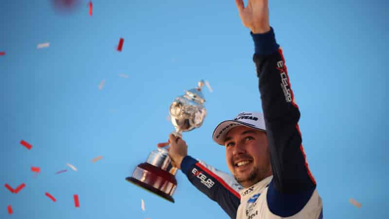 Tom Ingram holds the BTCC championship trophy in the air after winning the 2022 title