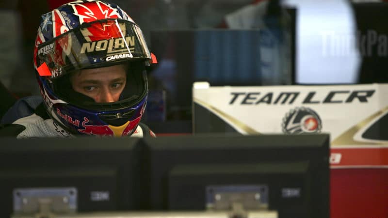 Casey-Stoner-sits-in-MotoGP-pit-garage-with-helmet-on