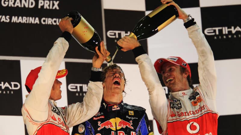 Sebastian Vettel celebrates 2010 F1 championship on Abu Dhabi podium with Lewis Hamilton and Jenson Button pouring rosewater over his head