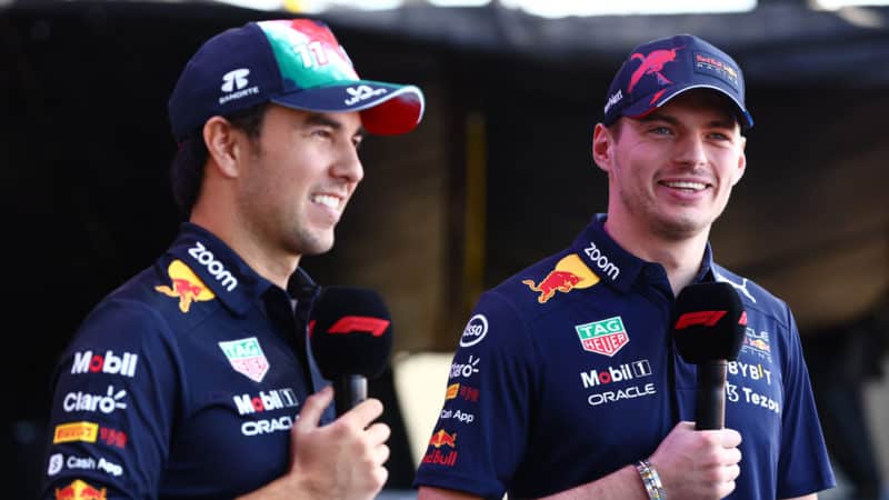 Sergio Perez and Max Verstappen smile as they stand next to each other in 2022