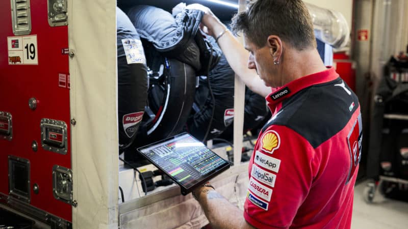Ducati MotoGP engineer looks at tyres and tyre data on a tablet computer