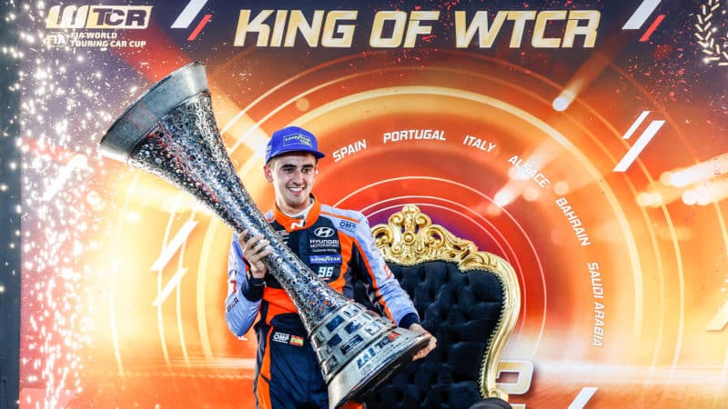 Mikel Azcona celebrates winning 2022 WTCR championship holding trophy in front of a throne