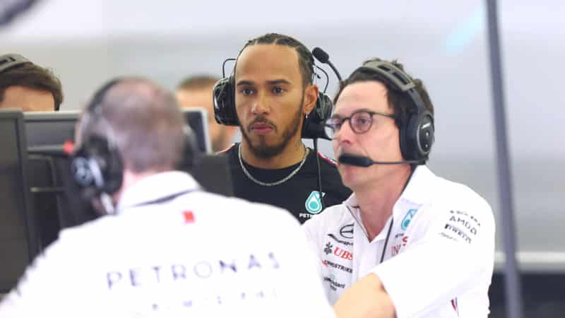 Lewis Hamilton with headphones on next to Toto Wolff in Mercedes F1 pit