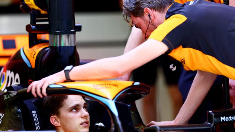 Oscar Piastri talks to team member from cockpit of 2023 McLaren F1 car