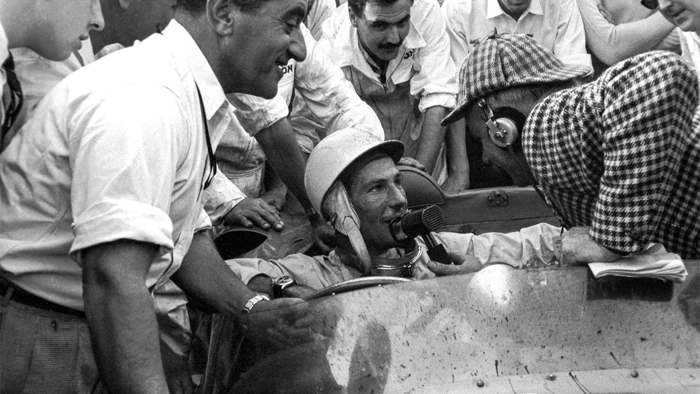 Stirling Moss behind the wheel with the crowd