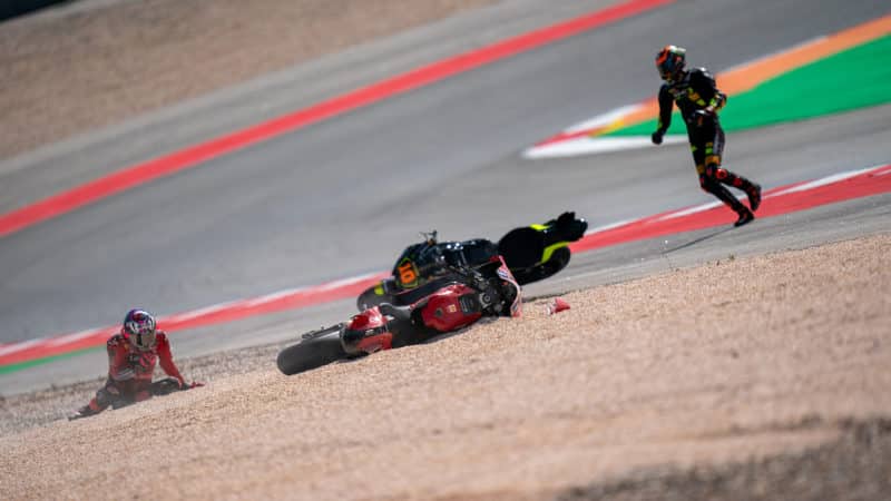 Luca Marini runs over to Enea Bastianini on the ground after crashing in 2022 MotoGP Portugal sprint race