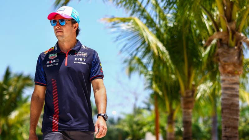 Sergio Perez walks under palm trees at Miami International Autodrome in 2023