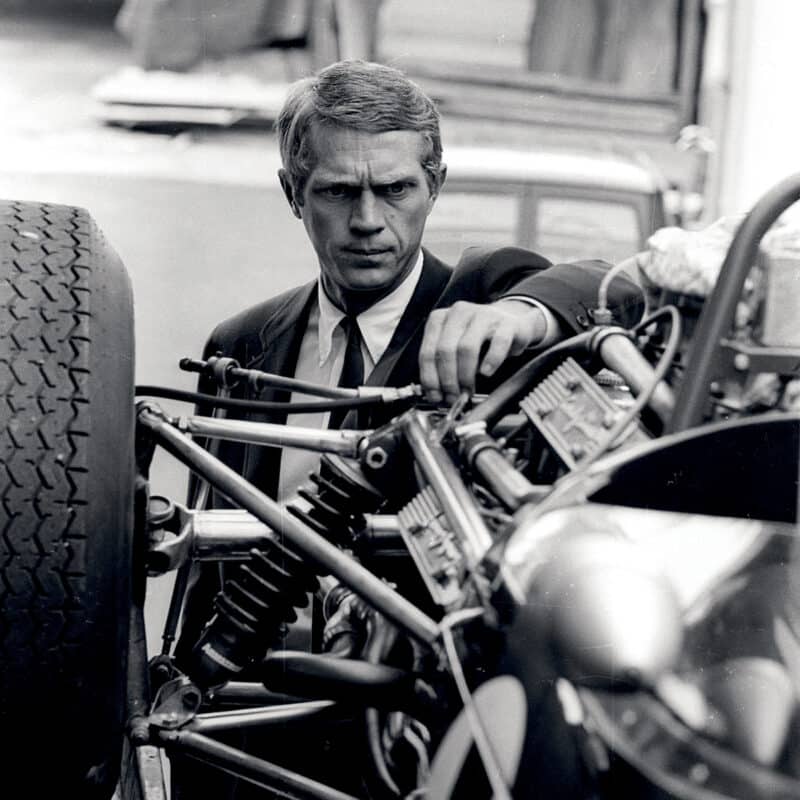 Steve McQueen tinkering with car on set