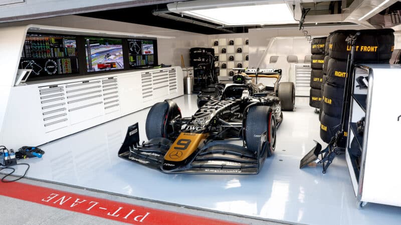 APXGP black and gold car in pit garage at 2023 British Grand Prix