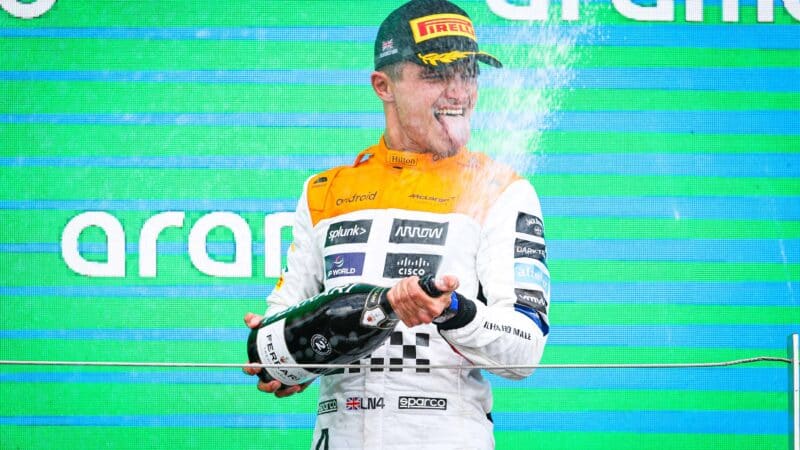 Lando-Norris-sprays-champagne-on-the-podium-at-2023-British-Grand-Prix