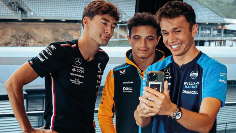 Albon shows his phone to Norris and Russell