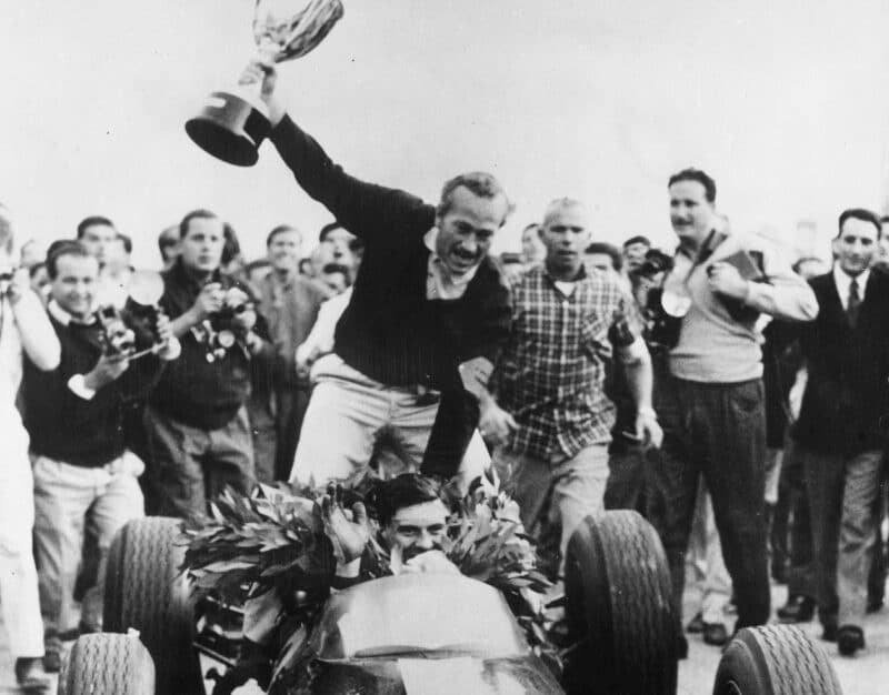 Colin Chapman sits on the Lotus 25 as Jim Clark drives away after winnng 1963 Italian Grand Prix