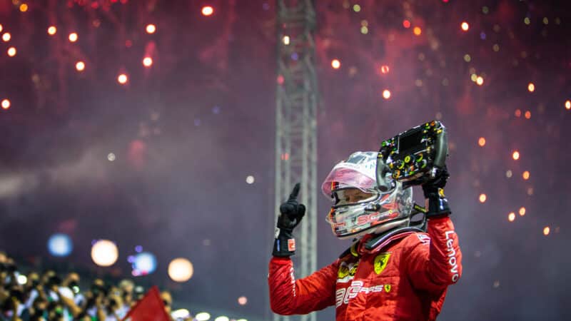 Sebastian Vettel celebrates winning the 2019 Singapore Grand Prix holding up his steering wheel under fireworks