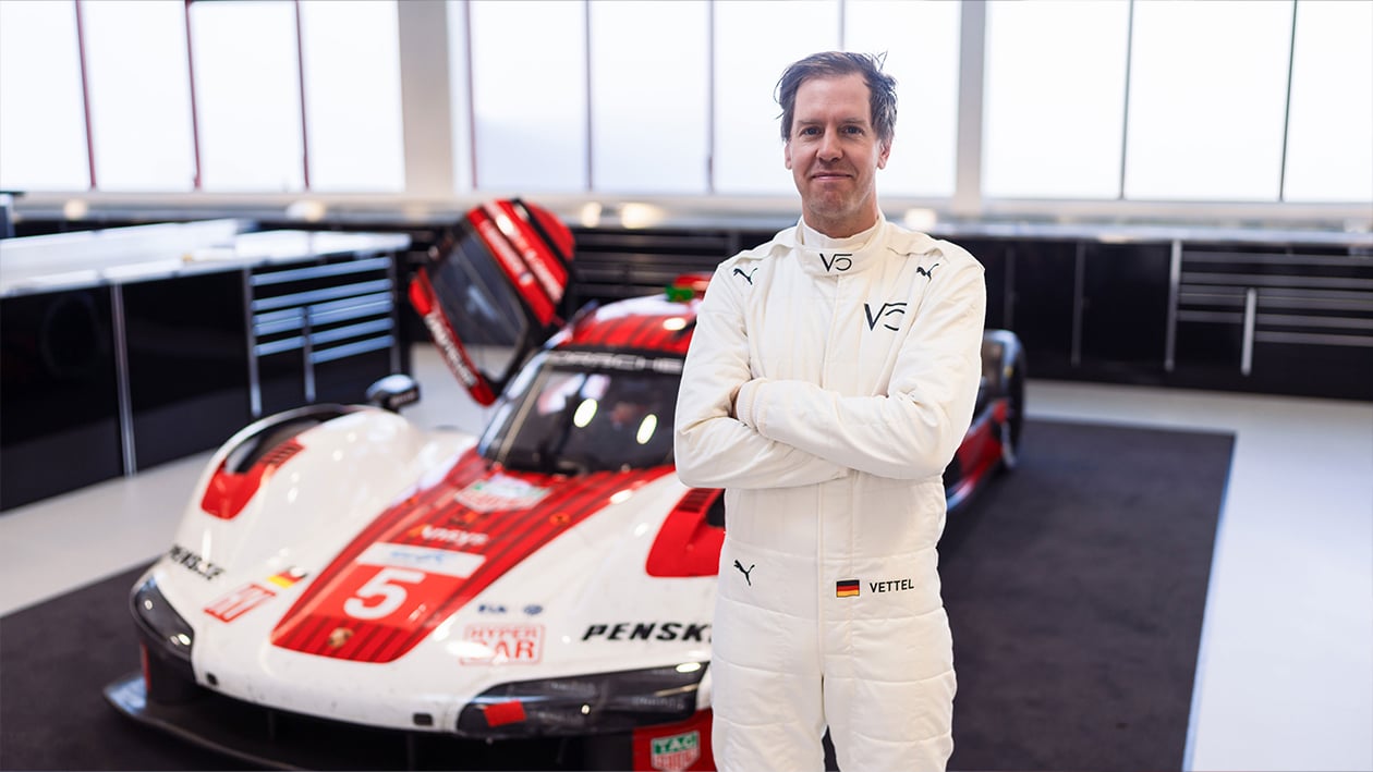 Sebastian Vettel stands in front of Porsche 963 Hypercar