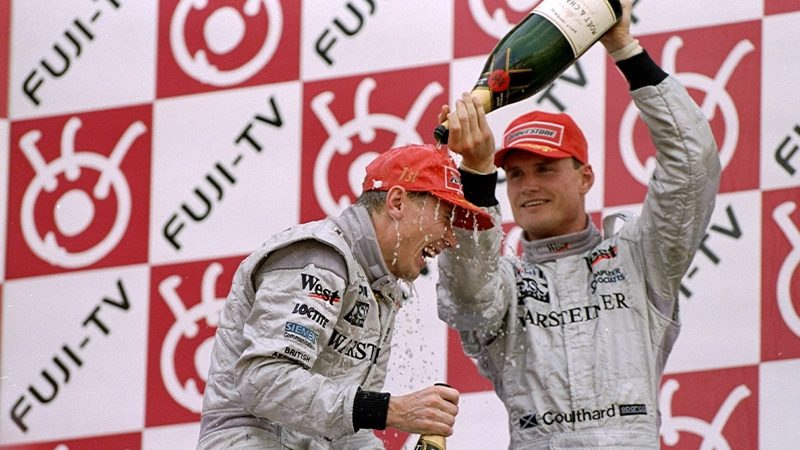 David Coulthard pours champagne over Mika Hakkinen on the 1998 Japanese GP podium