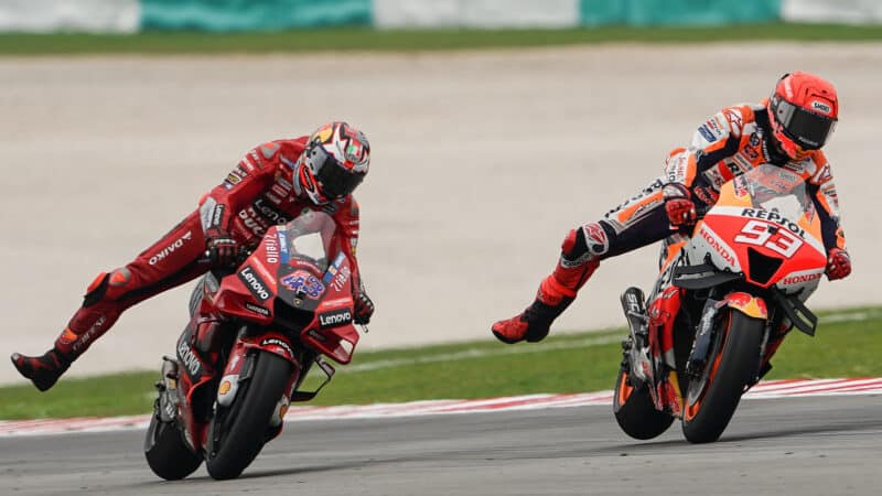 Jack Miller and Marc Marquez with right legs raised on track