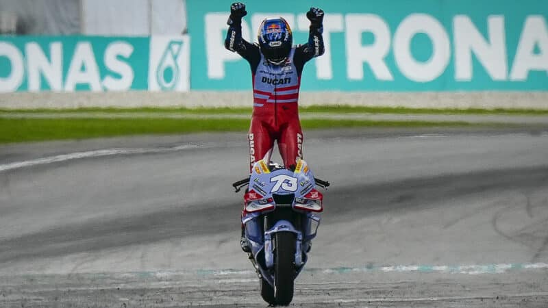Alex Marquez stands on his bike with arms raised after finishing second in MotoGP Malaysian GP