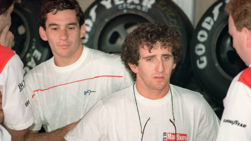 Ayrton Senna stands behind Alain Prost in the McLaren garage at the 1989 Monaco Grand Prix