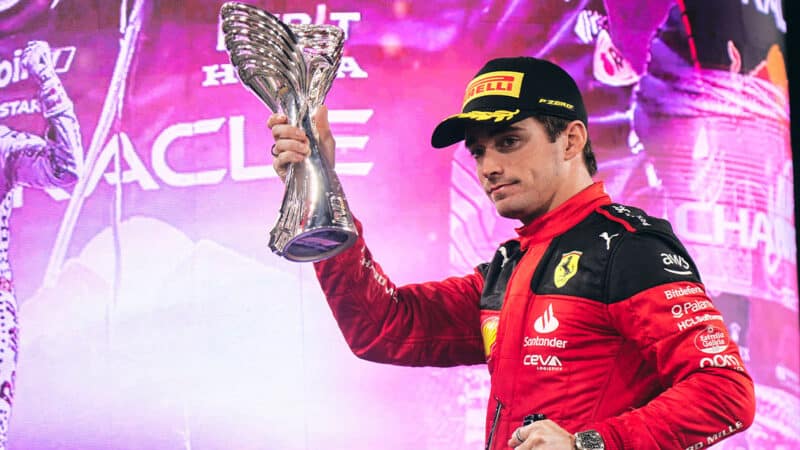 Charles Leclerc looks sombre holding trophy on the podium after 2023 F1 Abu Dhabi GP