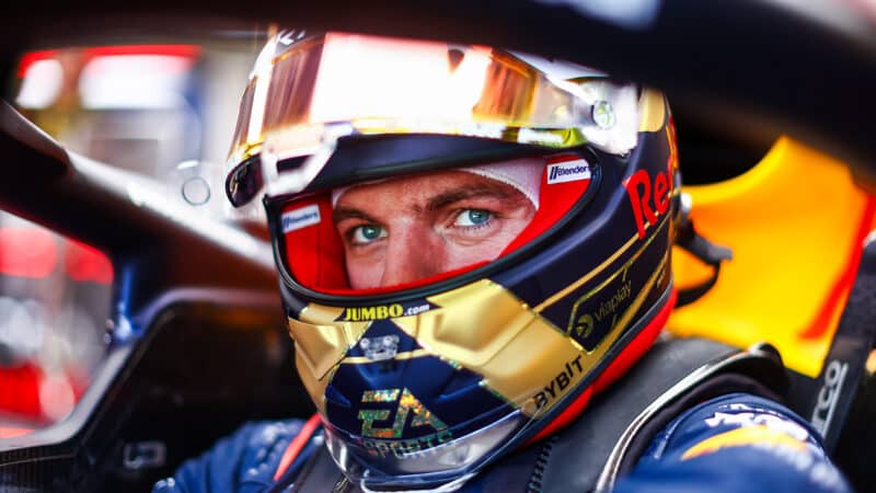 Max Verstappen sits in Red Bull cockpit with helmet on
