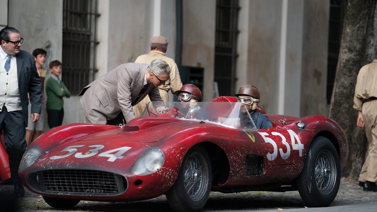 Enzo Ferrari (Adam Driver) leans in for a word with Peter Collins