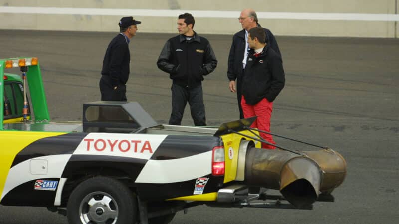 Gil de Ferran and Max Papis stand on Rockingham track as drying machine drives past