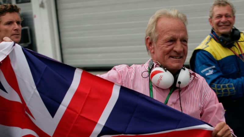 John Button holds up union Jack flag in F1 pitlane