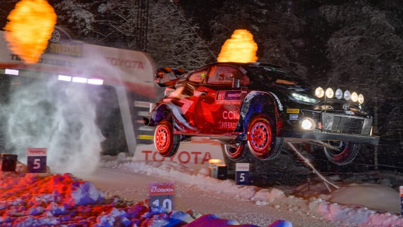 Toyota of Takamoto Katsuta in mid-air between a fire cannon on 2024 Rally Sweden