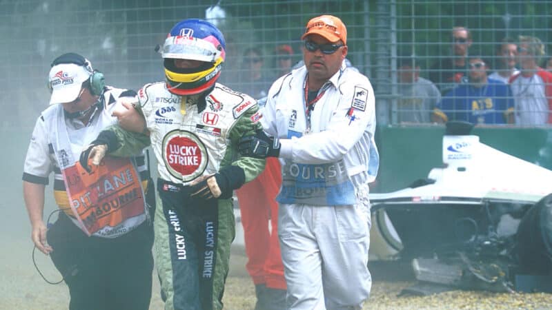 Jacques Villeneuve is led away from a crash at the 2001 Australian Grand Prix by marshals