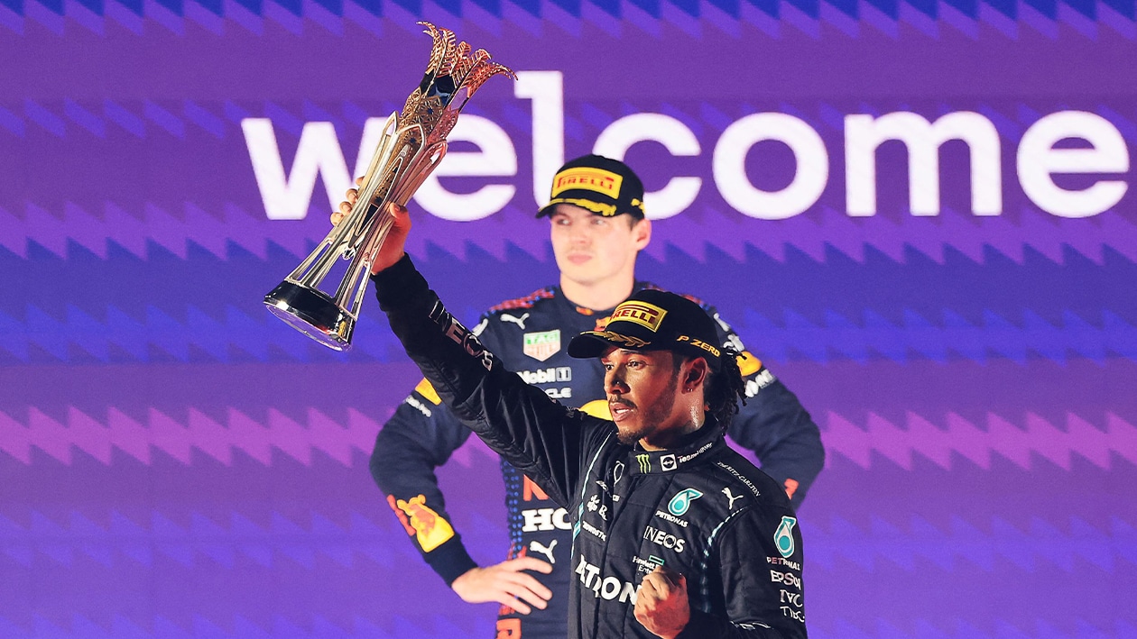 Lewis Hamilton holds up trophy for winning 2021 Saudi Arabian GPas Max Verstappen looks straightfaced behind him