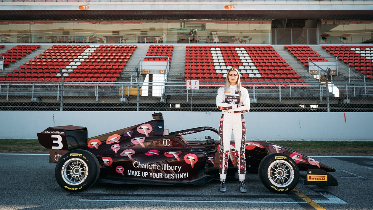 Lola Lovinfosse stands next to her Charlotte Tilbury sponsored F1 Academy car