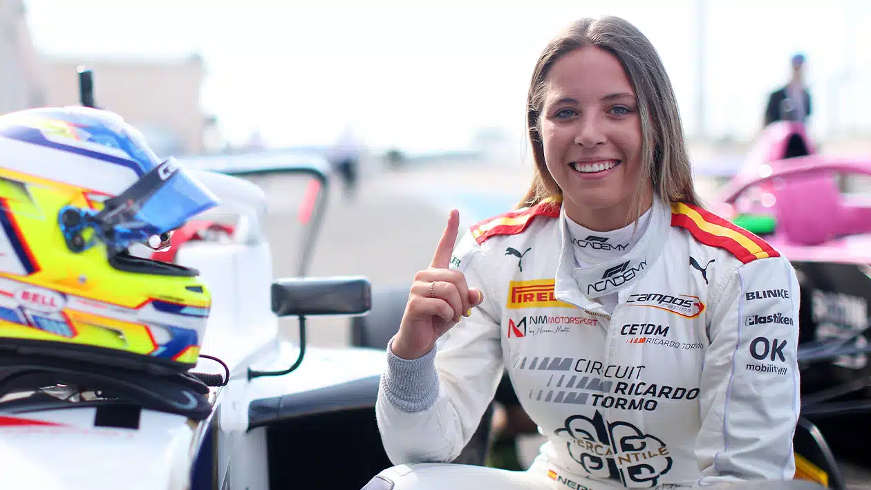 Nerea Marti poses with car and helmet with a finger in the air after winning 2023 F1 Academy round in France
